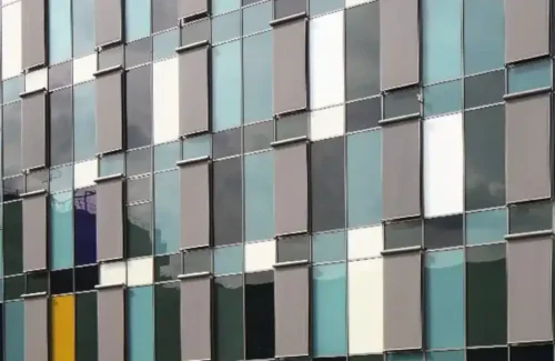 Moderne Fassade mit farbigen Flächen und vielen Fenstern.