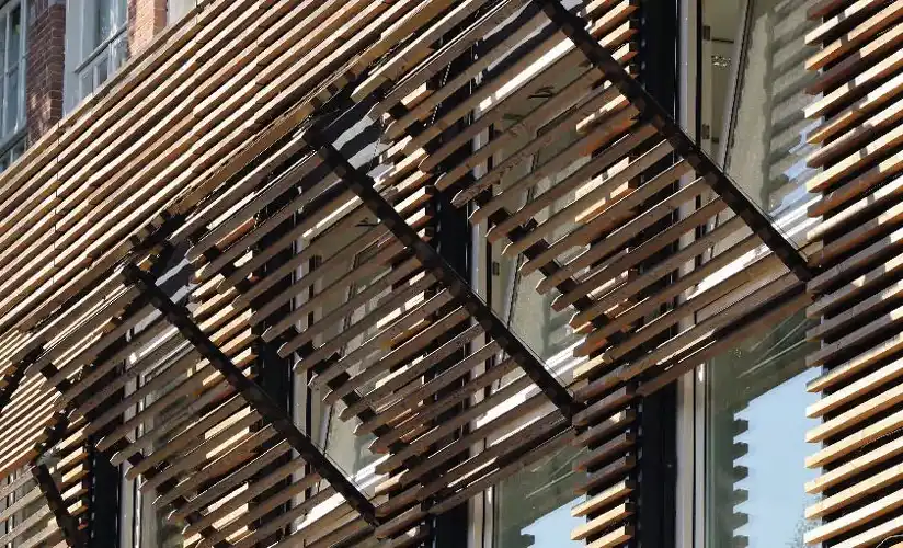 Mit Holzleisten verkleidete Fassade mit klappbaren Leistenelementen vor Holzfenstern