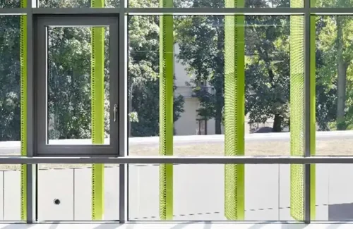 Glasfront mit grünen Läden und dunkel lackierten Kunststofffenstern